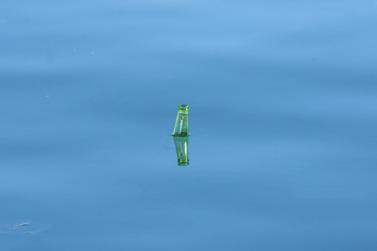 Une bouteille de bière Heineken de couleur verte flottant sur la Méditerranée.